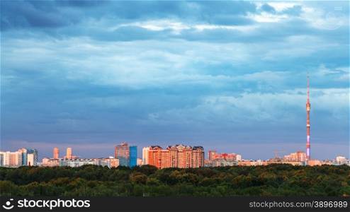 urban panorama with blue heavy clouds over illuminated by sunset cuty