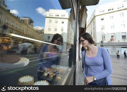 urban scene of young woman in front of sweet candy food store window