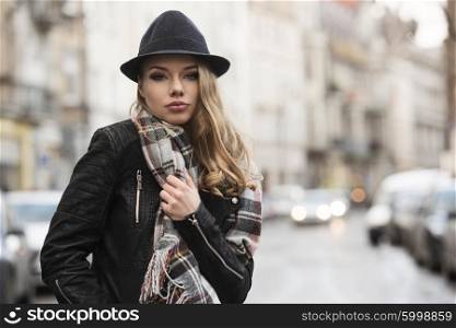 urban shot of fashion girl with casual dress , in a middle of a street , she has freckles on face , looking in camera with sweet expression