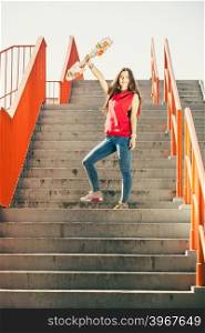 Urban skate girl with skateboard.. Cool skate young long haired girl holding skateboard standing on the urban stairs. Active lifestyle funky in summer. Outdoor trendy sport teen.