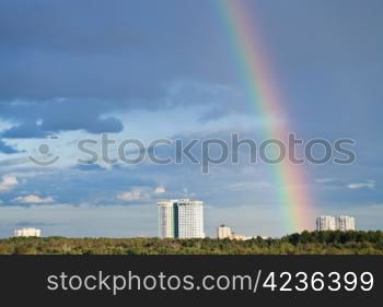 urban skyline with rainbow in dark blue sky