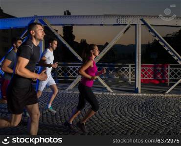 urban sports, group of young healthy people jogging across the bridge in the city at early morning in night