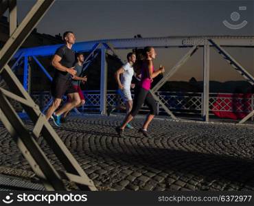 urban sports, group of young healthy people jogging across the bridge in the city at early morning in night
