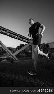 urban sports, young healthy man jogging across the bridge in the city at early morning in night