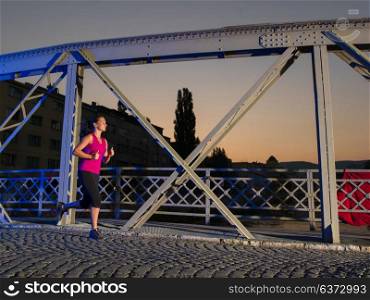 urban sports, young healthy woman jogging across the bridge in the city at early morning in night