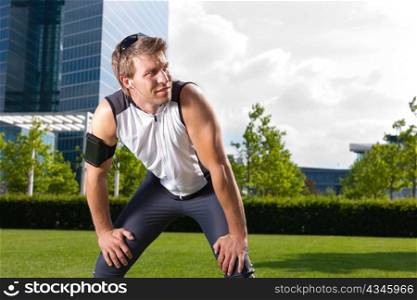 Urban sports - young man is doing warming up before running in the city on a beautiful summer day