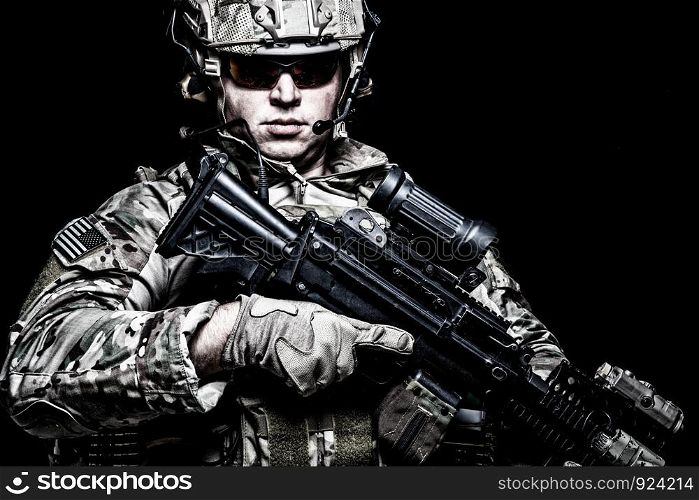 US army soldier, marine rider, special forces fighter in combat uniform, helmet and glasses, radio headset, armed assault rifle with night vision, thermal imagining, optical sight on black background. US army soldier with rifle on black background