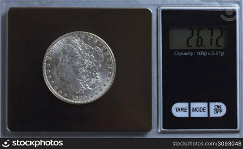 US Morgan silver dollar being weighed on digital scale for verification