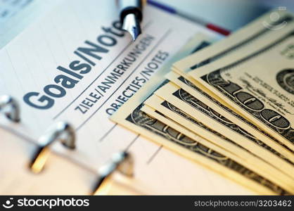US paper currency and a pen on a personal organizer