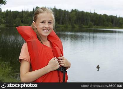 USA, Alaska, teenage girl wearing life jacket by lake, portrait