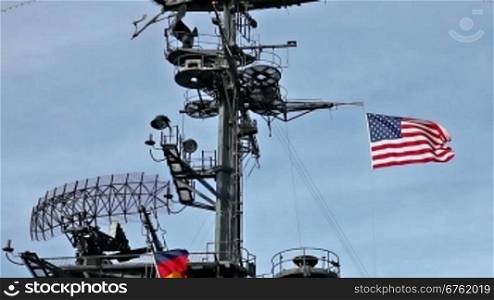 USA flag and antennas on carrier control tower in blue sky