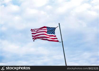 USA Flag Blowing in the Wind on High Flag Pole with Sky Background