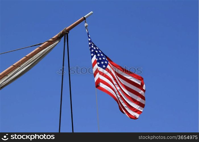 USA flag on an old sail ship with blue sky as background