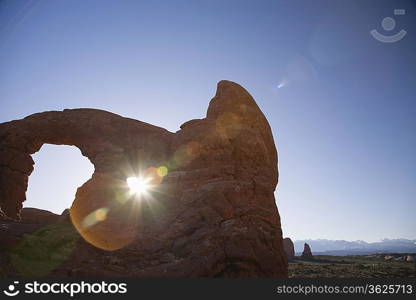 USA, sun shining through rock formation in desert