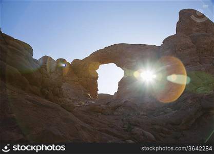 USA, sun shining through rock formation in desert