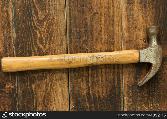 Used and rusty hammer on a wooden background