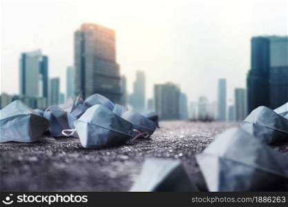 Used Medical Mask on ground. Challenging of Business during Coronavirus. Low angle View. blurred City Town as background. Metaphor Conceptual photo