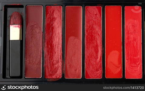 used palette with different shades of thick lipstick, close up