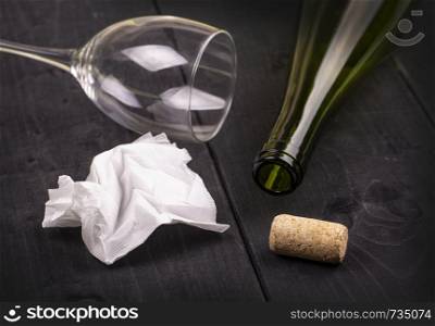 used white crumpled paper napkin and an empty wine bottle with cork on old wooden table