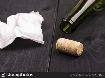 used white crumpled paper napkin and an empty wine bottle with cork on old wooden table