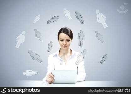 Using modern technologies. Attractive businesswoman sitting at table and using tablet