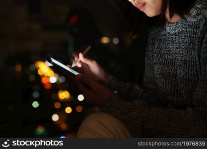 Using stylus pen on digital tablet at night, lifestyle at night in city