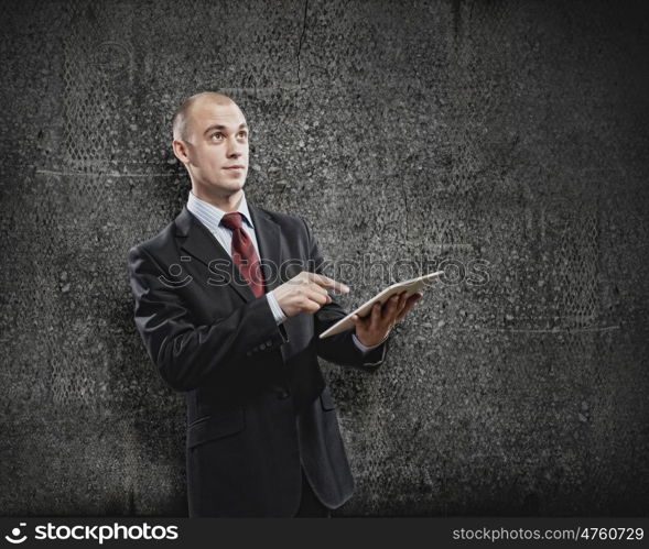 Using tablet pc. Handsome elegant businessman holding tablet pc in hands