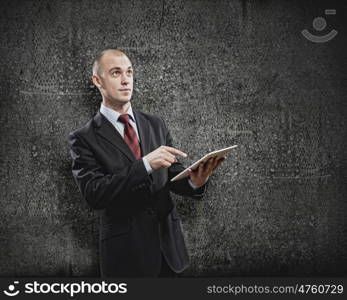 Using tablet pc. Handsome elegant businessman holding tablet pc in hands