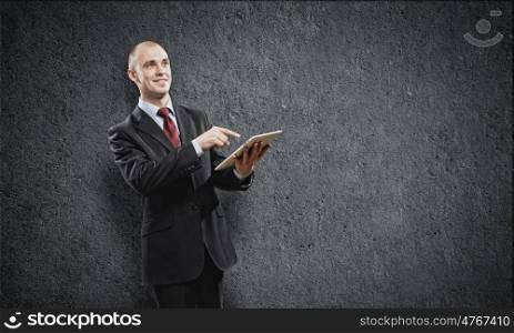 Using tablet pc. Handsome elegant businessman holding tablet pc in hands