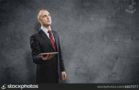 Using tablet pc. Handsome elegant businessman holding tablet pc in hands