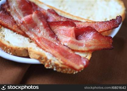 Using thick-sliced bacon to make a sandwich on whole-grain bread with mayonnaise