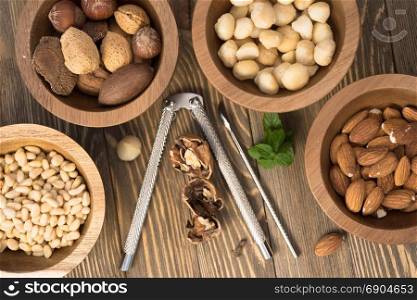 Utensils and nut filled bowls sit on wooden table