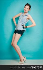 Vacation and summer fashion. Full length fashionable girl in jeans shirt shorts and high heels on blue