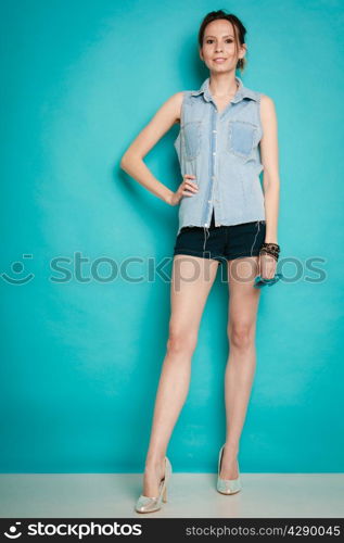 Vacation and summer fashion. Full length fashionable girl in jeans shirt shorts and high heels on blue