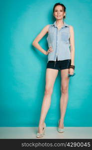 Vacation and summer fashion. Full length fashionable girl in jeans shirt shorts and high heels on blue