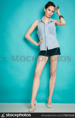 Vacation and summer fashion. Full length fashionable girl in jeans shirt shorts and high heels on blue