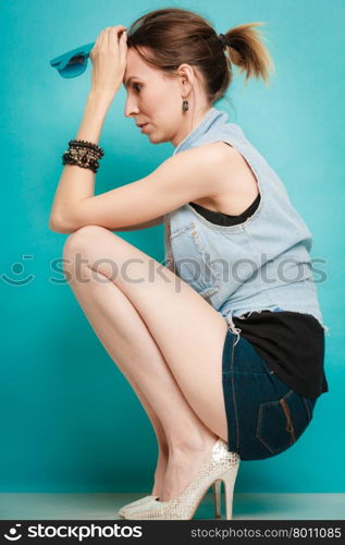 Vacation and summer fashion. Full length fashionable girl in jeans shirt shorts and high heels on blue