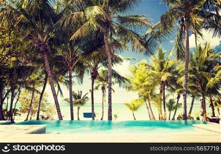 vacation, beach, summer and leisure concept - swimming pool on tropical beach