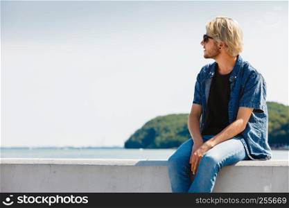 Vacation, contemplation concept. Nostalgic man sitting relaxing and enjoying weather during summertime, outdoor shot on sunny day. Sitting man relaxing, enjoying summertime