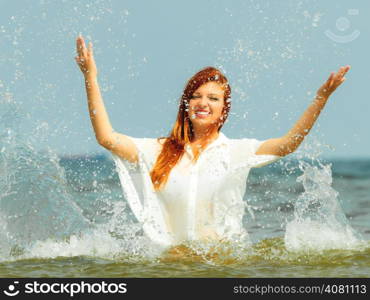 Vacation. Girl splashing water on the coast. Young woman having fun relaxing on the sea. Summertime.