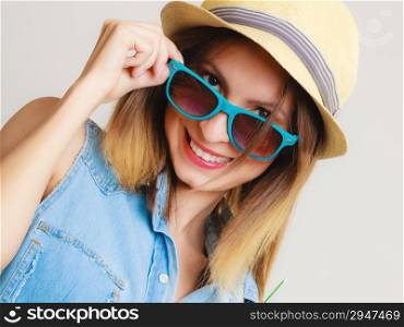 Vacation. Happy girl in summer clothes blue sunglasses and straw hat. Portrait of smiling woman tourist on gray.