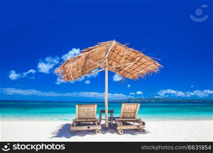 Vacation holidays background - two beach lounge chairs under tent on beach. Lounge chairs under tent on beach