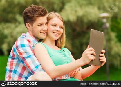 vacation, holidays, technology and friendship concept - smiling couple with tablet pc computer making selfie in park