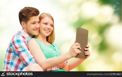 vacation, holidays, technology and love concept - smiling couple with tablet pc computer taking selfie over green background