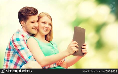 vacation, holidays, technology and love concept - smiling couple with tablet pc computer taking selfie over green background