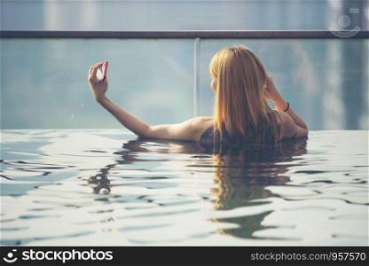 Vacation in Kuala-Lumpur. Young woman enjoy swimming in roof top pool with beautiful city view