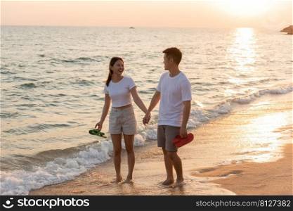 Vacation loving couple walking on beach together at sunset landscape, relaxing vacation travel summer, Asian man and woman in love holding hands walks along the sandy seashore