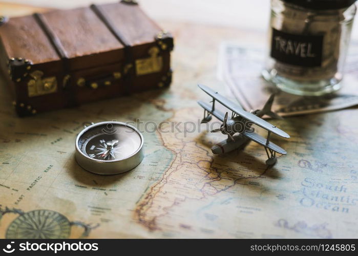 Vacation money saving in a glass with toy airplane and compass on map, Travel concept. Toy airplane and compass on map, Travel concept