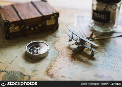 Vacation money saving in a glass with toy airplane and compass on map, Travel concept. Toy airplane and compass on map, Travel concept