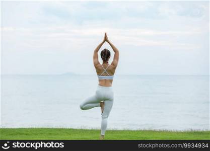 Vacation of Beautiful Attractive Asian woman relaxing in yoga lotus pose on green grass and beach with beautiful sea in Tropical island,Feeling comfortable and relax in holiday,Vacations Concept
